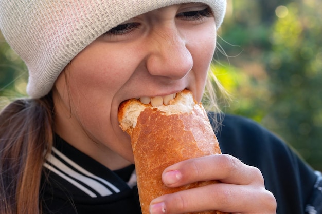 Photo girl bites off a piece of bread outdoors in the village