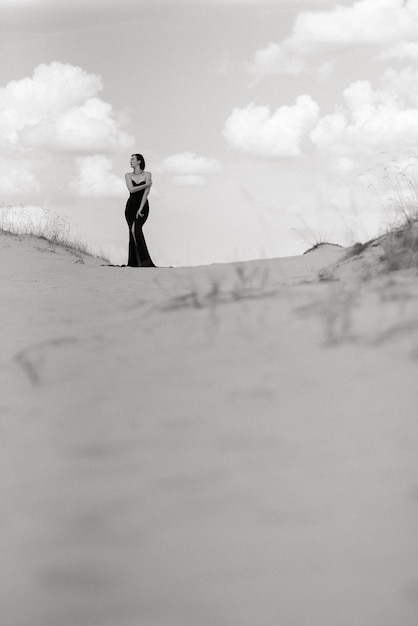 Girl in a black long dress in a sandy desert