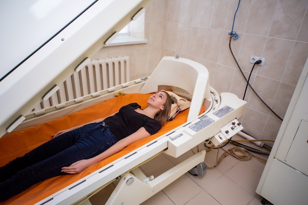 A girl in a black T-shirt lies in a hyperbaric chamber, oxygen therapy