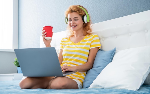 Girl blogger smile with coffee in headphones blogger girl at home blogger girl work with laptop