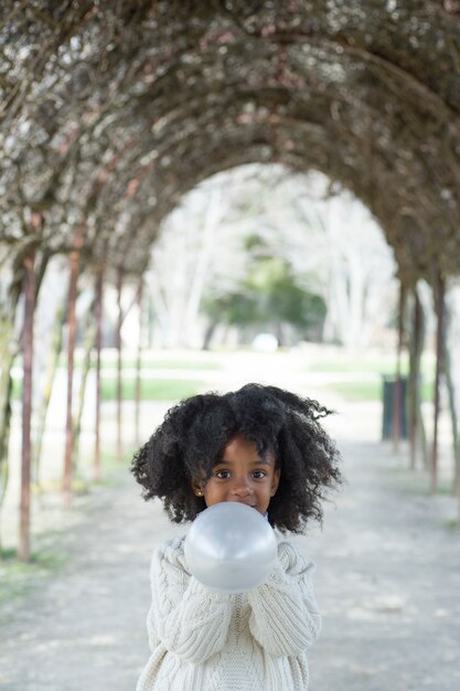 Girl blowing balloon outside