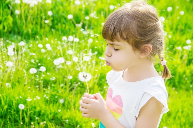 Girl blowing dandelions in the air selective focus