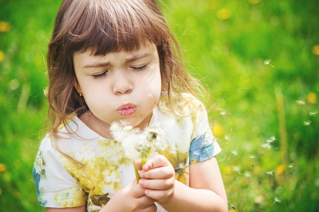 Girl blowing dandelions in the air. selective focus.