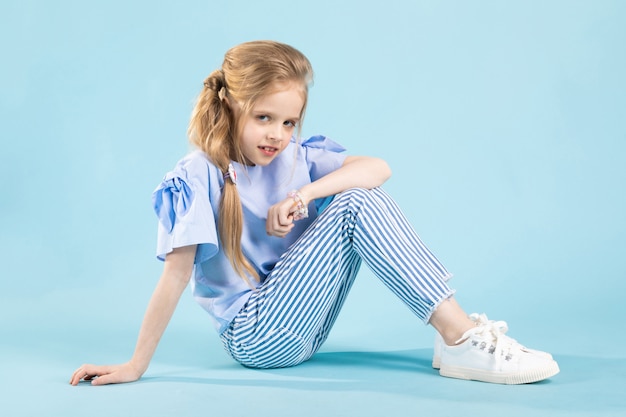 A girl in blue clothes is sitting on blue .