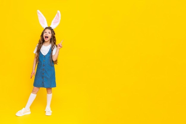 A girl in a blue dress with bunny ears on a yellow background