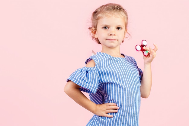 Girl in blue stripped shirt is playing red spinner in hand