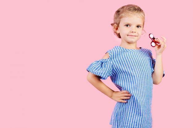 Girl in blue stripped shirt is playing red spinner in hand