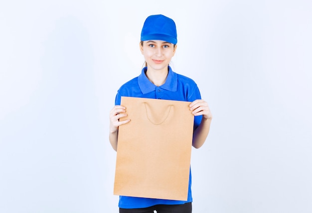 Girl in blue uniform holding a cardboard shopping bag.