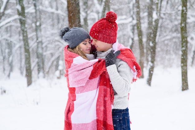 Girl and boy make warm each other in winter forest