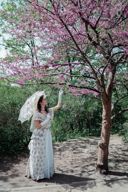 Girl bride in vintage dress near flowering tree