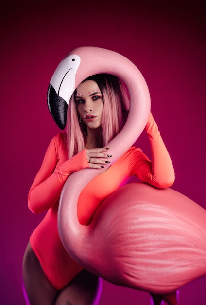 The girl in a bright bodysuit poses with a large Flamingo figurine