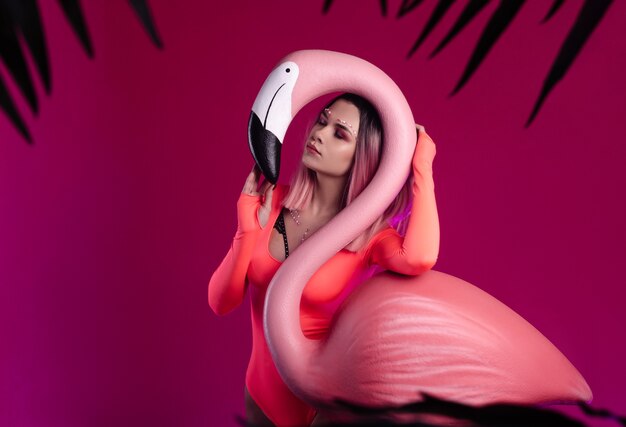 The girl in a bright bodysuit poses with a large Flamingo figurine