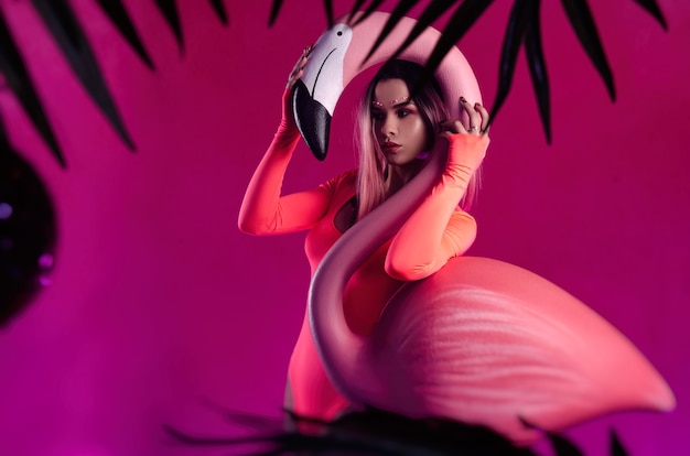 The girl in a bright bodysuit poses with a large Flamingo figurine