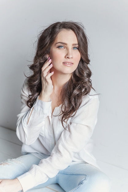 Girl in bright room sitting against white wall