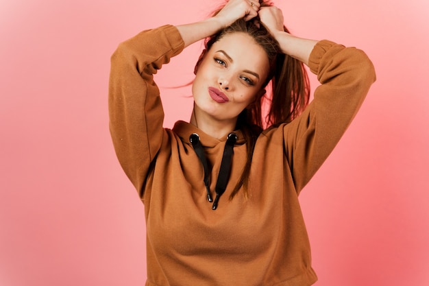 Girl in a brown sweater on a pink background