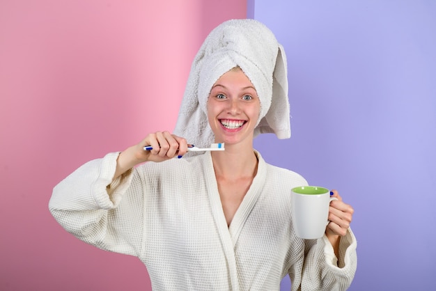 Girl brushing teeth woman in white tender bathrobe daily routine morning procedures awakening sleep