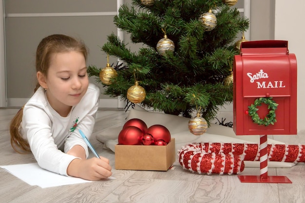 Girl by the Christmas tree writes a letter to Santa Christmas content