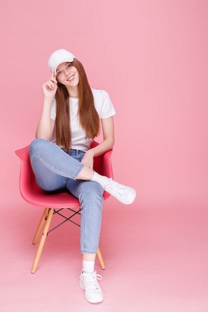 Girl in cap sits on pink