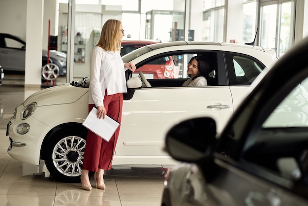 A girl in a car dealership buys a small city car.