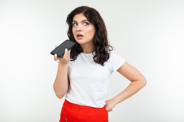 Girl carefully talking on the phone over the speakerphone on a white background