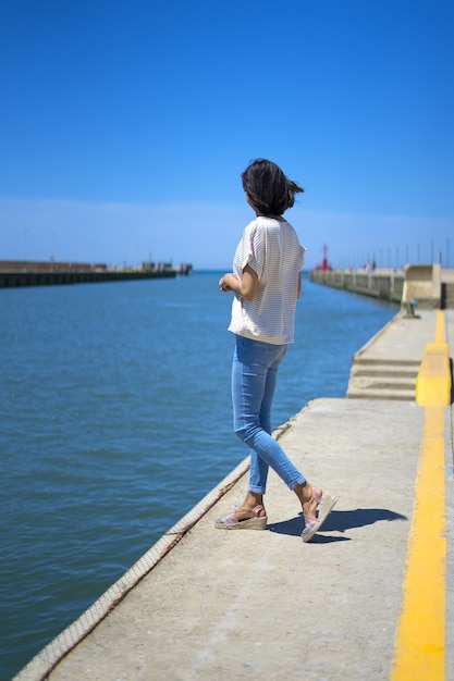 Photo girl in casual clothes on vacation walking through an italian port in summer time