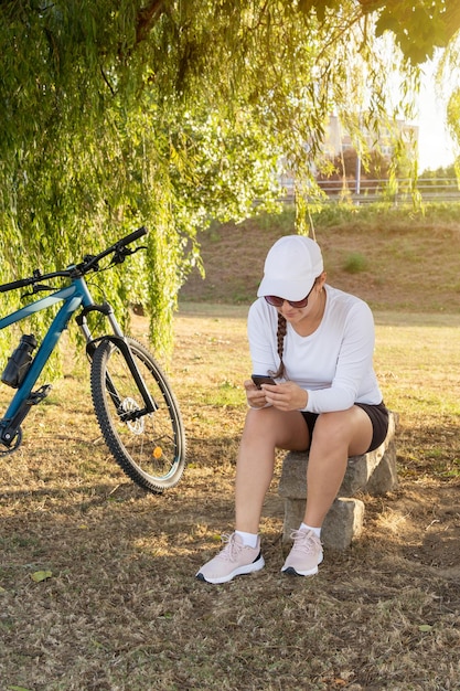 Girl checks social media on her cell phone after exercising on her bike