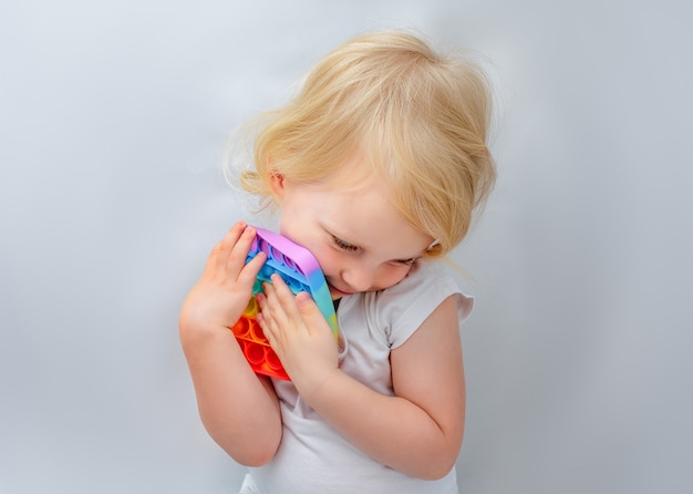 A girl child hugs her favorite colorful antistress sensory toys push pop it