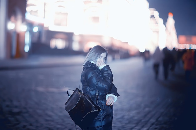 girl christmas lights evening decorated city, a young model on the background of urban decorations and garlands, night city lights