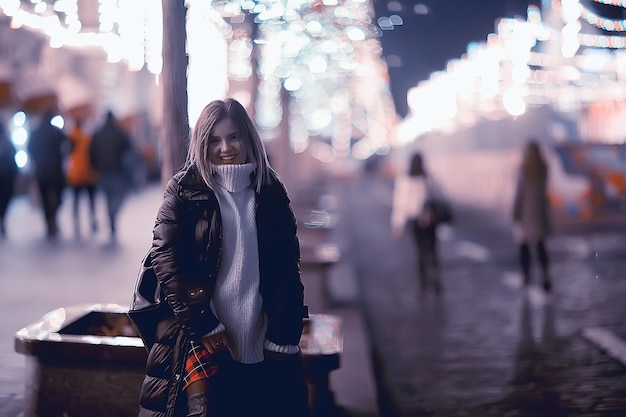 girl christmas lights evening decorated city, a young model on the background of urban decorations and garlands, night city lights