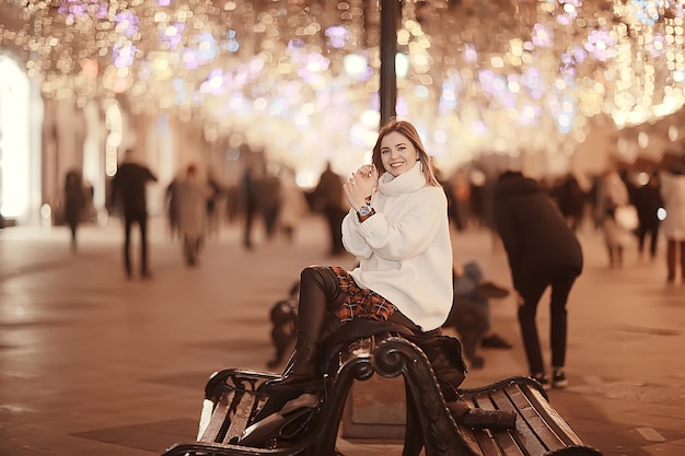 girl christmas lights evening decorated city, a young model on the background of urban decorations and garlands, night city lights