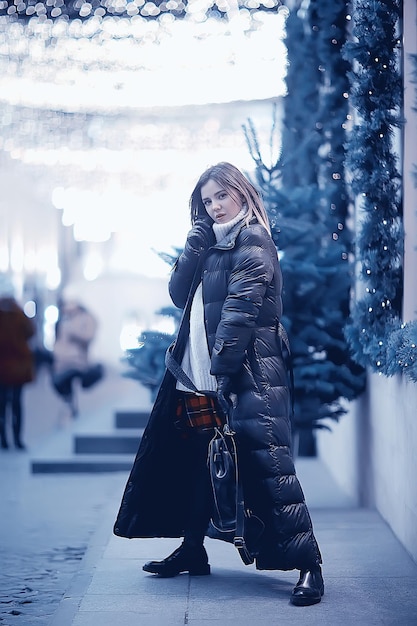 girl christmas lights evening decorated city, a young model on the background of urban decorations and garlands, night city lights