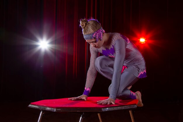 Girl circus acrobat gymnast on stage on a dark background