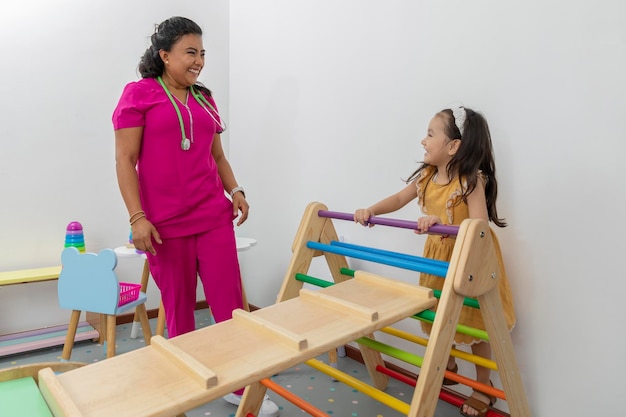 Girl climbing a game in the pediatric office while the pediatrician observes her