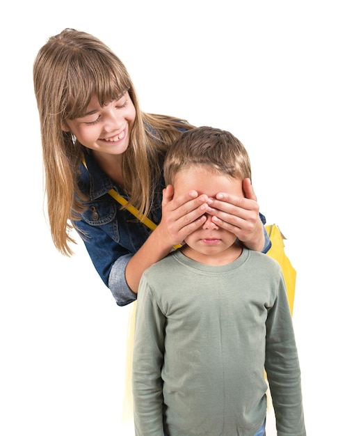 The girl closes her brothers eyes isolated on white background funny couple children laughing with a