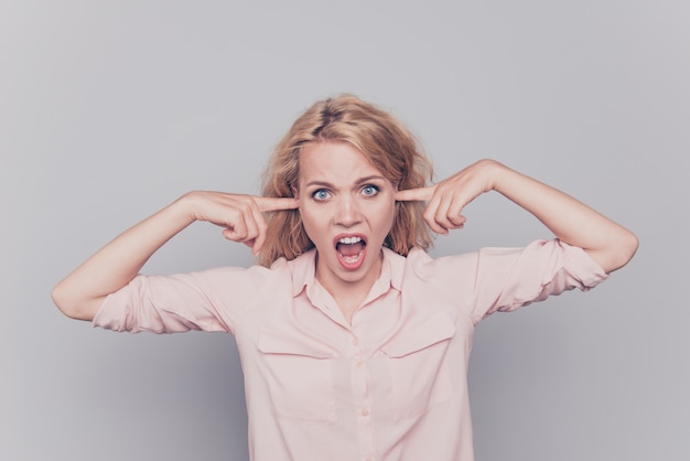 Girl closing ears with fingers do not listen isolated over grey