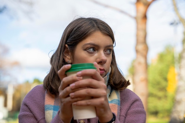 Girl in a coat eats street food standing at a table in an outdoor cafe