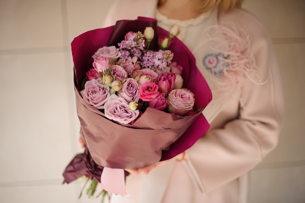 Girl in the coat holding a bouquet of purple violet flowers