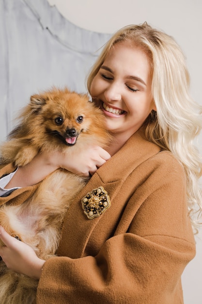 Girl in a coat with a brooch hugs a dog of the breed Pomeranian spitz