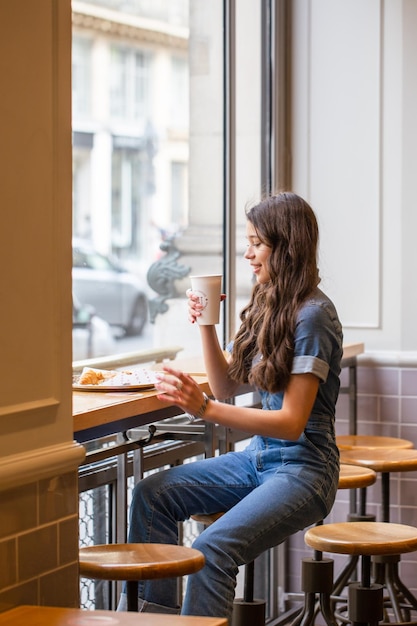 The girl in the coffee shop drinks coffee. Girl with coffee. Beautiful girl on vacation. With a cup