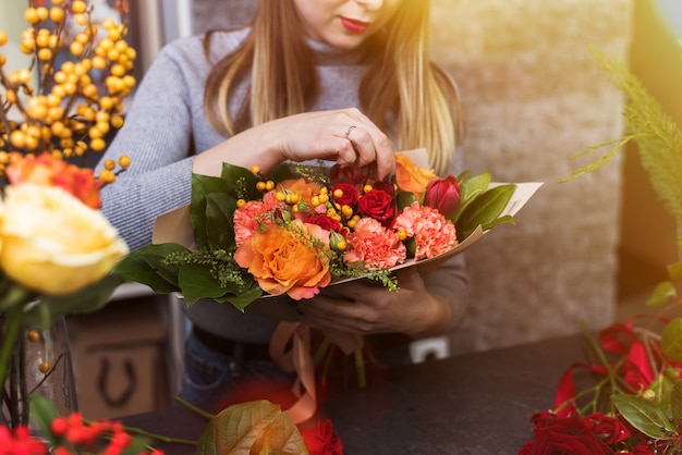 Girl collects a bouquet of various flowers. Small business