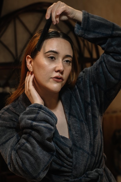 Girl combing her hair dressed in a bathrobe