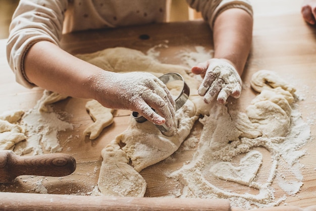 Girl cook at home cookies in a kitchen a child stirs flour knead the dough on the table by hand