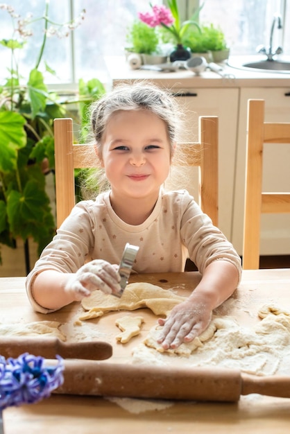 Girl cooks at home in a bright kitchen a child stirs flour on the table baby helps mom and laughs