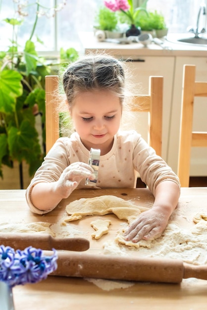 Girl cooks at home in a bright kitchen a child stirs flour on the table baby helps mom and laughs