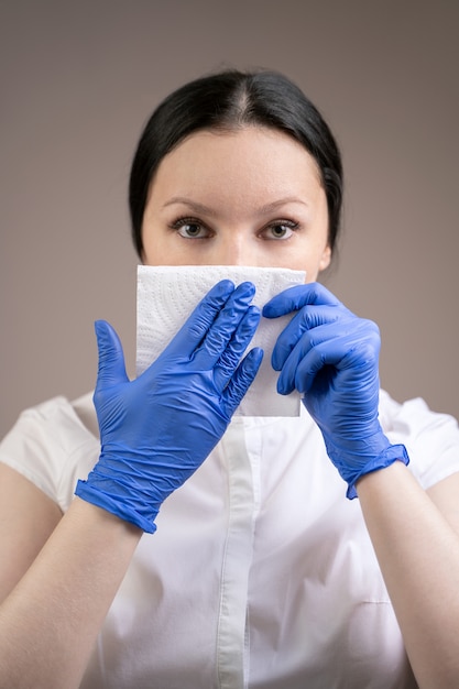 The girl covers her mouth with a napkin when coughing.