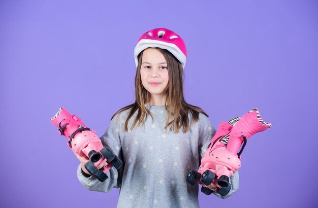 Girl cute teen wear helmet and roller skates on violet background Active leisure and lifestyle Roller skating teen hobby Joyful teen going to ride Sporty teen girl Ready to roller skating