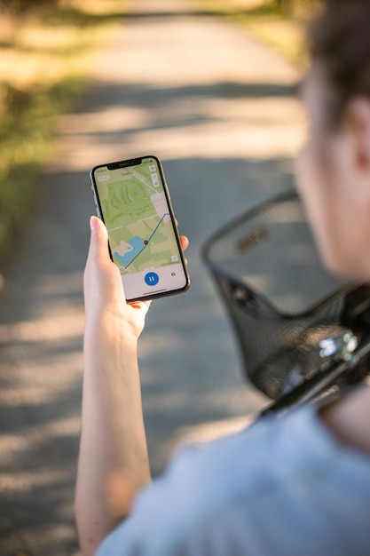 Girl cyclist looks at a map on her phone and plots a route for a trip for a GPS navigator