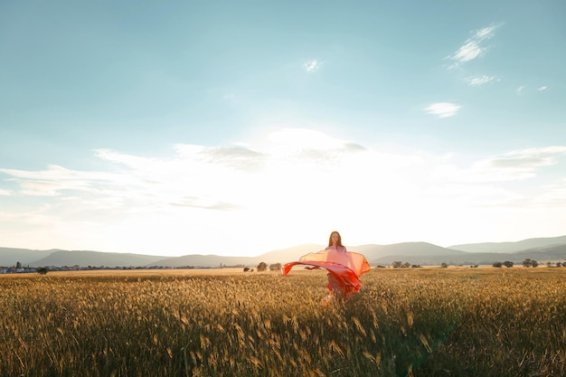 Girl dancing in a field in a beautiful pink dress at sunset