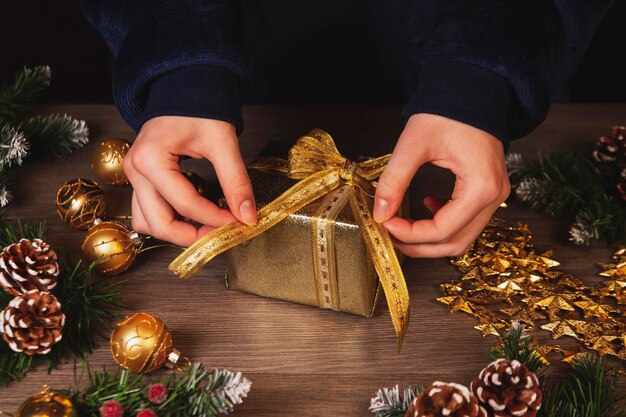 Girl decorates Christmas gifts Top view on wooden table background Celebrating Christmas