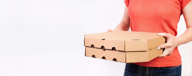 Girl delivering pizza in cardboard boxes on a white background with copy space